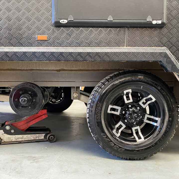 dual axle caravan jacked up with one wheel removed